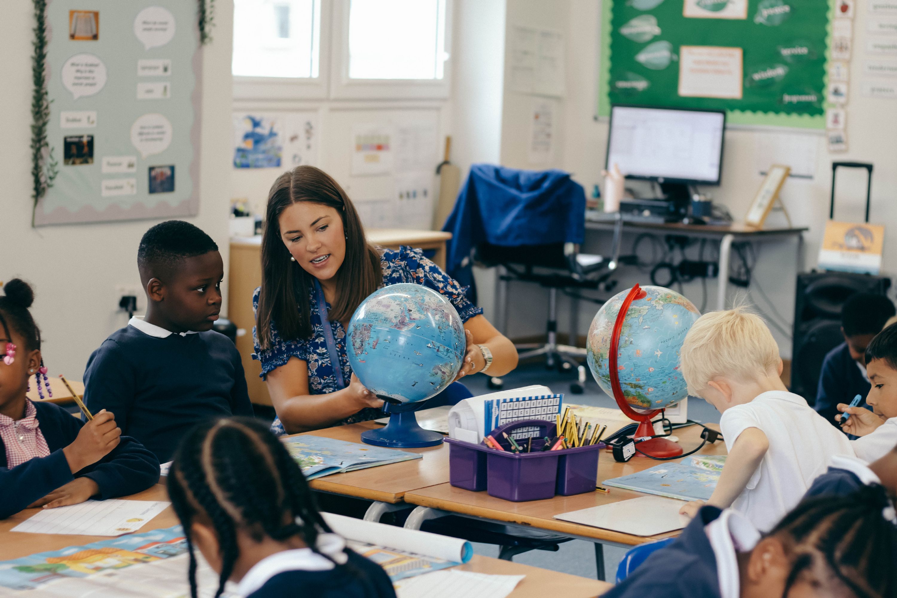 Teacher showing a pupil a globe in a classroom